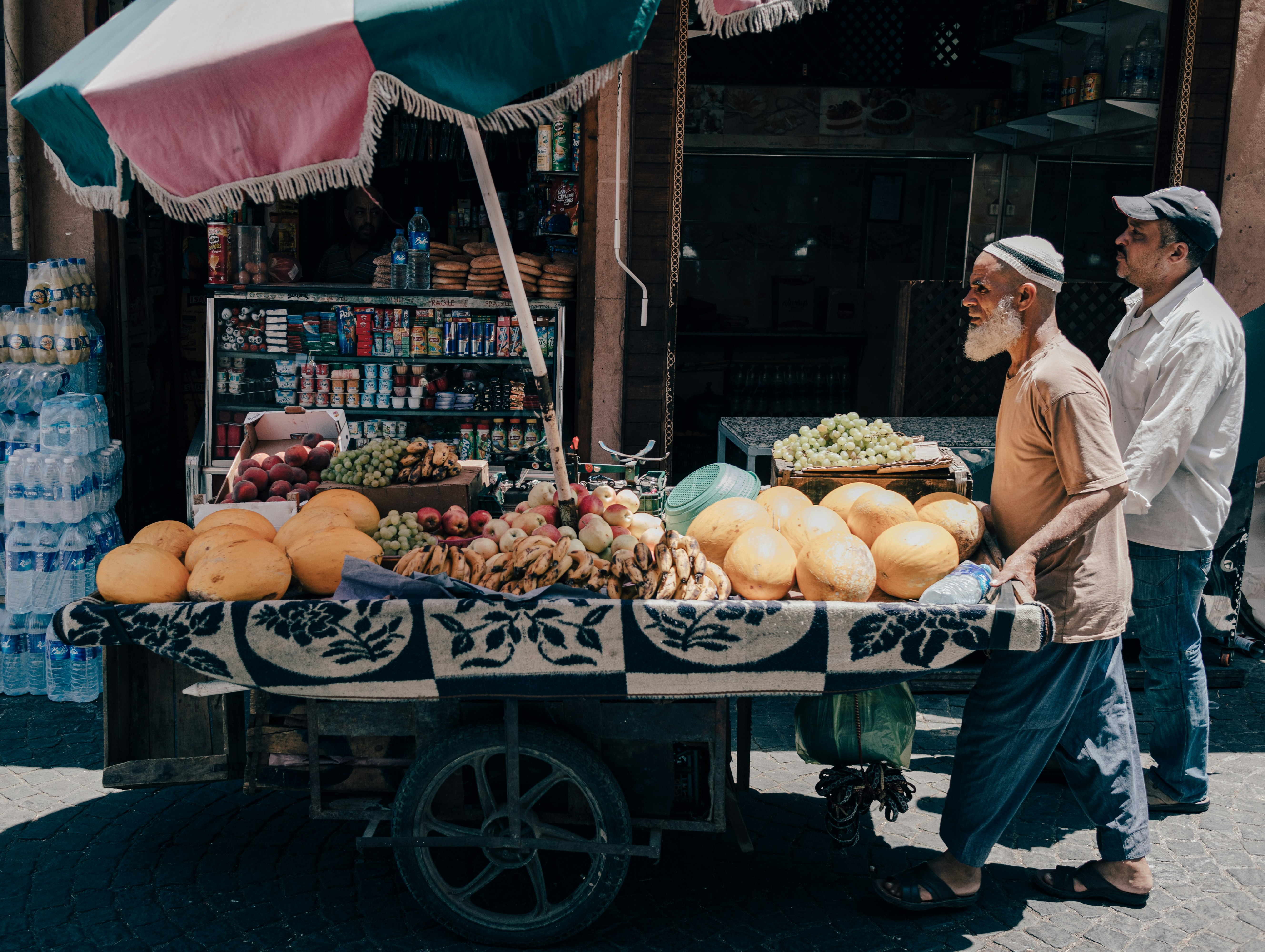 man standing beside food kart at daytime